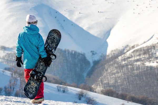snowboarder girl standing hold snowboard in the blue sky