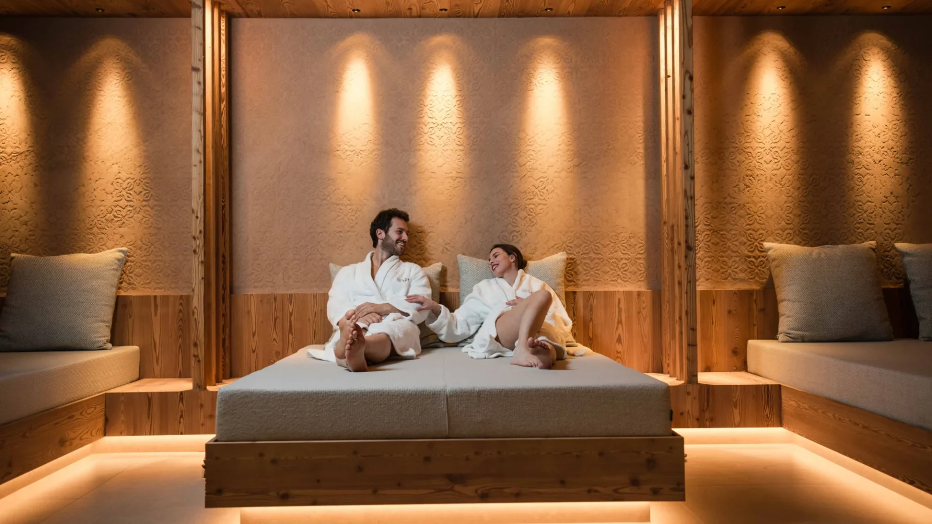 Ein Paar entspannt sich in einem Spa-Bereich auf einem großen Bett.