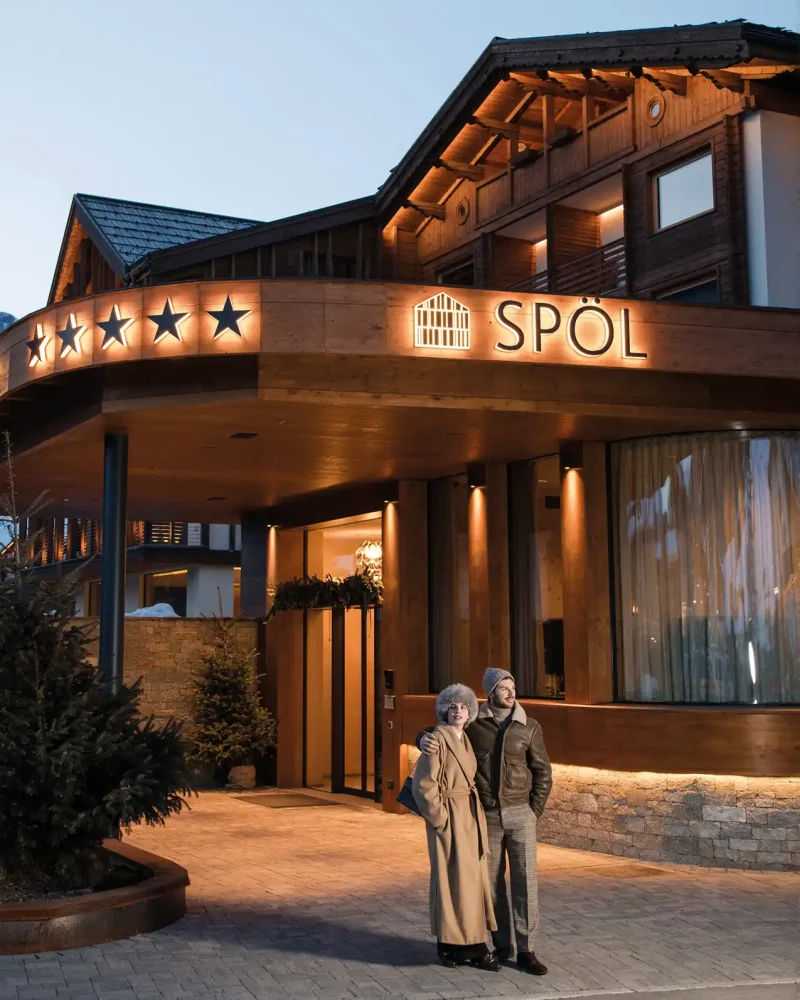 Esterno di un hotel di lusso con due persone che passeggiano davanti all'ingresso.